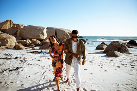 Laughing Couple Walking Arm in Arm on the Beachの写真素材