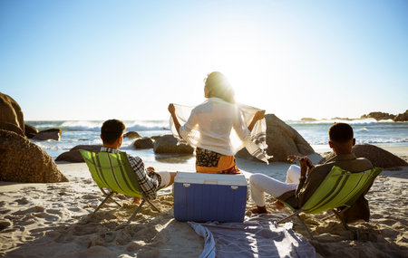 Three People Relaxing and Watching the Sea at Sunsetの写真素材