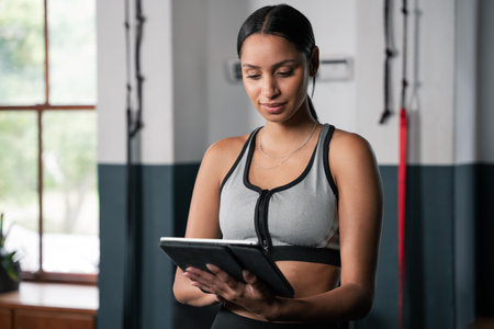 A blond woman is using a tablet gadget while working out at the gym