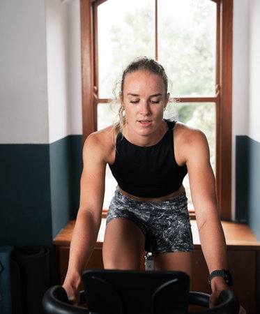 a woman is riding an exercise bike in front of a windowの写真素材