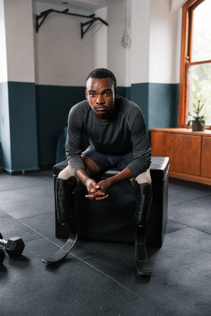 A gym member with a prosthetic leg sits on a chair by a windowの写真素材