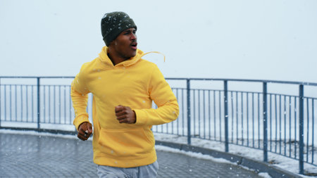 Man athlete in a bright sweater runs down the street in winterの写真素材