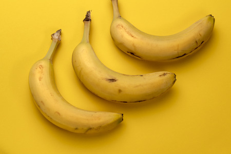 Three banana fruits isolated on yellow backgroundの写真素材