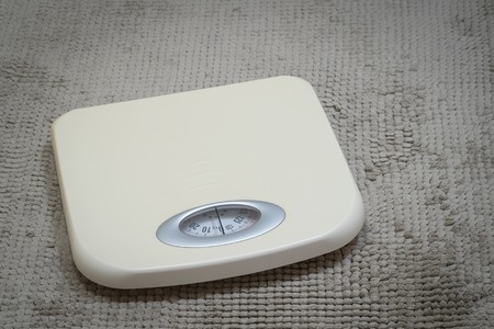 Photo of a weight scale on a bathroom carpet floorの写真素材