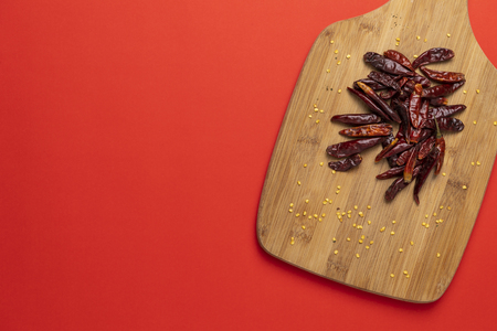 Group of dried asian chilli papers, hot chinese capsicum on the wooden chopping board on red backgroundの写真素材