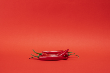 Image of red narrow long spicy chili peppers isolated on the red backgroundの写真素材