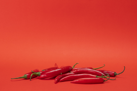Group of red narrow long spicy chili peppers isolated on the red backgroundの写真素材