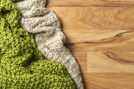 Wool blanket, white and green, knitted large chunky yarn. Close-up of knitted blankets on wooden background.の写真素材