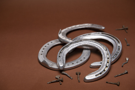 Pile of horseshoes and nails isolated on a brown background with copy spaceの写真素材