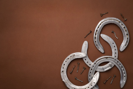 Pile of horseshoes and nails isolated on a brown background with copy spaceの写真素材