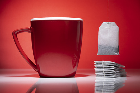 Red mug and a tea bags isolated on the red backgroundの写真素材