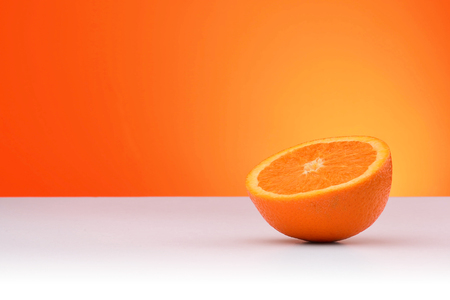A piece of orange isolated on an orange and white background with space for textの写真素材