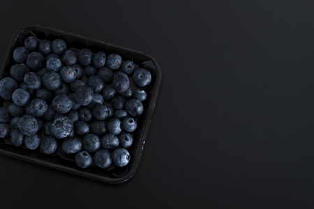 Bunch of blue berries on a tray isolated on black backgroundの写真素材