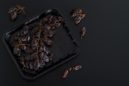 Bunch of dried sultanas on a tray isolated on black backgroundの写真素材
