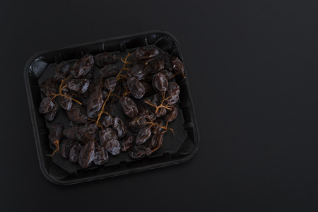 Bunch of dried sultanas on a tray isolated on black backgroundの写真素材