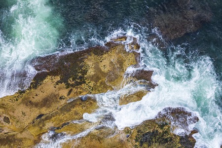 Aerial, overhead view of waves and a rocky shoreline in Sydney, Australiaの写真素材