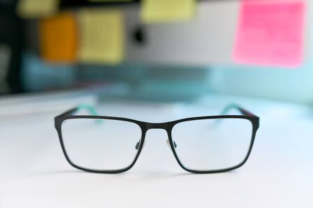 Close up image of black and green eyeglasses on the desk with blur backgroundの写真素材