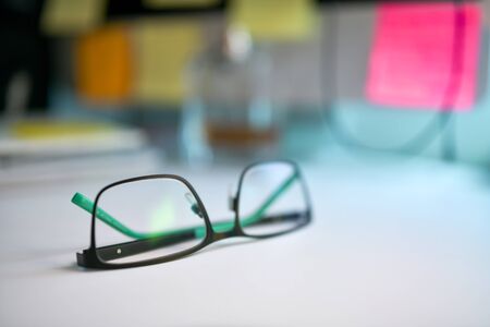 Close up image of black and green eyeglasses on the desk with blur backgroundの写真素材