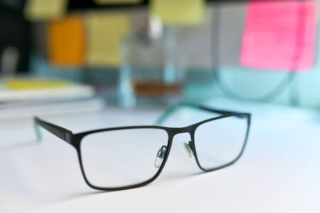 Close up image of black and green eyeglasses on the desk with blur backgroundの写真素材