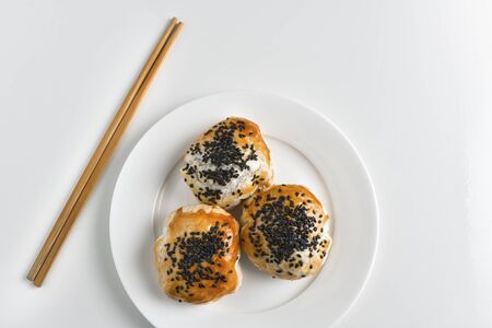 Chinese red bean paste cakes and chopsticks on ceramic plate, isolated on white backgroundの写真素材