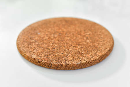 Close up of a cork placemat on white table with blurred background