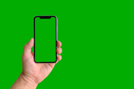 Man holding mobile phone with green screen on green background, closeup of hand. Space for textの写真素材