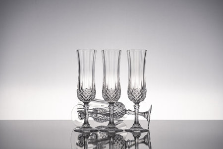 Cut glass crystal stemware champagne flute, isolated on shiny gray surface with gray background.