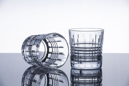 Crystal whiskey glasses on a reflective surface. Isolated object. Dramatic modern background. Contemporary design.の写真素材