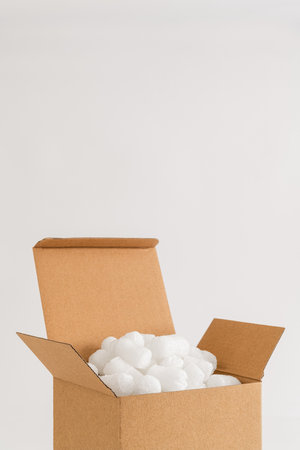 Cardboard box isolated on the white background filled with packing peanuts. Copy space.の写真素材