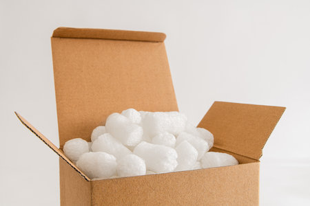 Cardboard box isolated on the white background filled with packing peanutsの写真素材