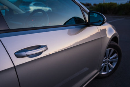 Close up photo of a car door handle with a side mirror in the backgroundの写真素材