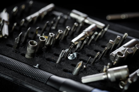 Unorganized screwdriver kit with aluminum bit driver on black tray. Driver handle with magnetic bit socket and knurled grip.の写真素材