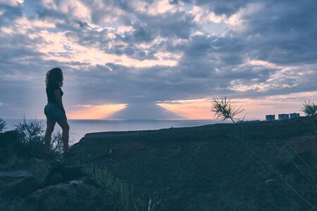 silhouette of girl watching the sunset from the top of a ravine in Tenerife