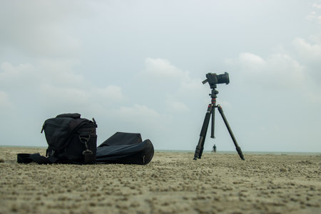 black backpack and camera on the beach with foggy sky background.の写真素材