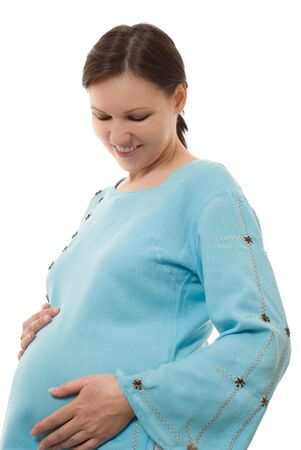 young pregnant woman stands and pats bellyの写真素材