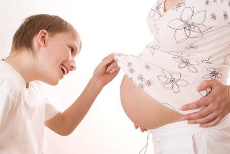 son surprised looks on the stomach of a pregnant motherの写真素材