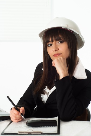 beautiful girl sitting in the construction helmet at the officeの写真素材