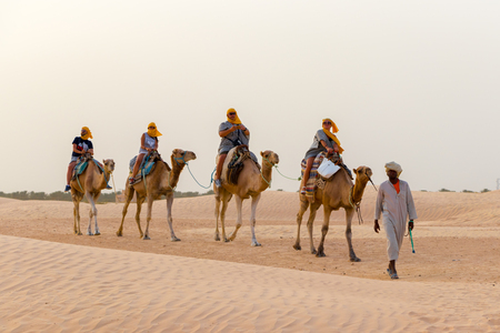 Tourists ride on camels guided by a local man, in the Sahara desert, Tunisia, Africaのeditorial素材