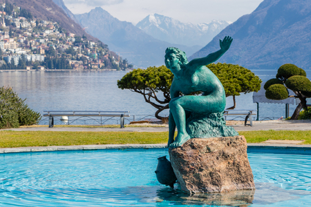 A fountain by Lake Lugano with a beautiful statue in the middle of blue water in the Italian part of Switzerlandの写真素材