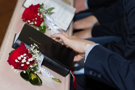 A picture of the Holy Bible with red roses in churchの写真素材