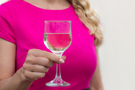 Close up of a business woman holding a wine glass on a white background in stylish magenta dressの写真素材
