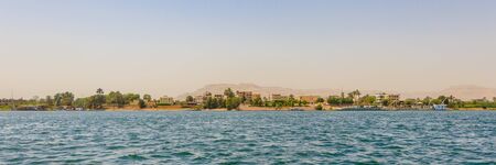 Luxor, Egypt - April 16, 2019: Residential buildings on the Nile river with sailboats in Luxor, Egyptの写真素材