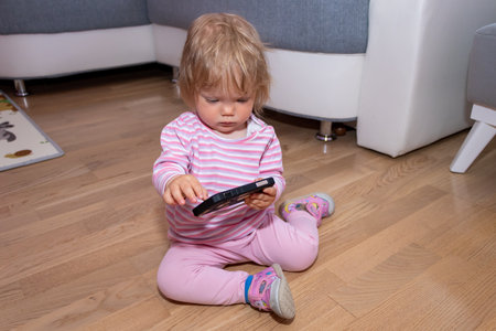 The baby girl at home is playing and touching a mobile phone. Baby addiction to gadgets