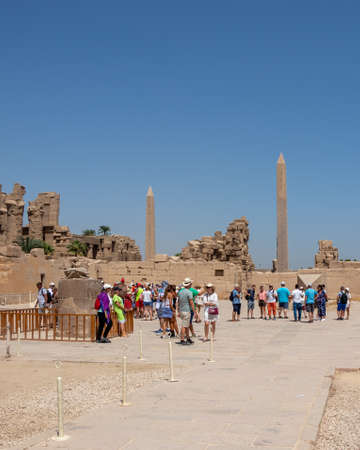 Luxor, Egypt - September 21, 2021: Travel tour group wanders through Karnak Temple. Egyptian landmark with hieroglyphics, decayed temples, obelisks, towers, and other buildings.のeditorial素材