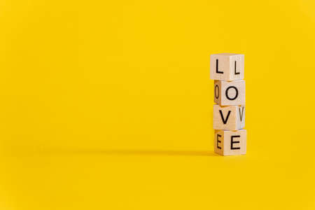 Wooden cubes with the word Love on a colorful yellow background.の写真素材