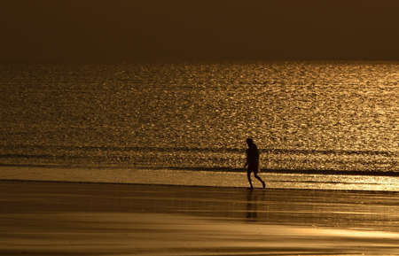 fisherman running across a seashore in the morningの写真素材
