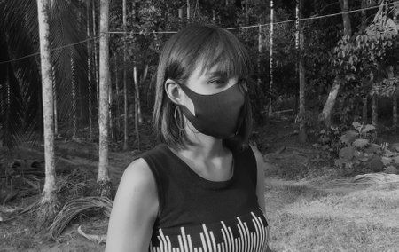 Ranong/ Thailand- 4.1.2020: Asian woman masked a protective in beautiful at garden, wearing protective black mask, with backpack standing alone enjoying the nature, new normal lifestyle concept.のeditorial素材