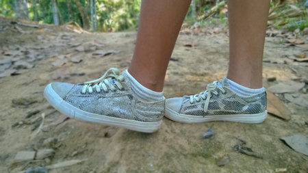 View on legs and shoes of walking teen girl in The garden, with low section of a human leg, during...