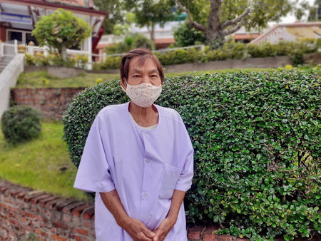 Ranong, Thailand- 10.04.2020: Senior woman standing pose, with wearing a face mask during Covid-19 virus. Disease and illness protection. Sanitary masks cloth for coronavirus prevention.のeditorial素材