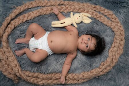 Baby boy wearing diaper, New born kid during tummy time with toy bearの写真素材